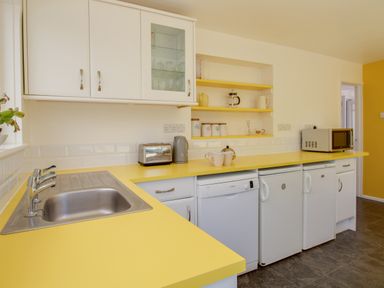 A kitchen with yellow countertops white cabinets a stainless steel sink and appliances at Waterson in Osmington