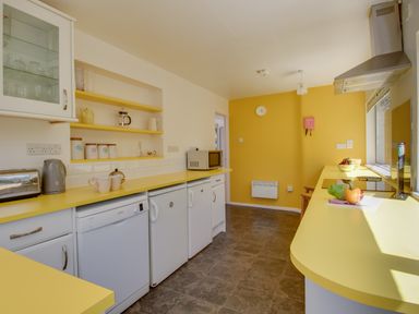 A kitchen with yellow countertops white cabinets and appliances at Waterson in Osmington