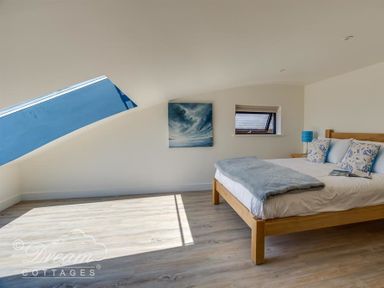 A bedroom with a wooden bed a skylight window and a small window at The Wave in Eype