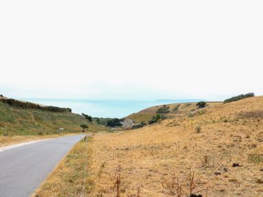 A countryside road beside dry grass fields and hills at Woodlands Cottage in Ringstead