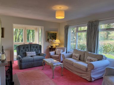 A sitting room with two sofas armchair coffee table lamp and windows at Woodlands Cottage in Ringstead