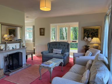 A living room with a fireplace armchairs a sofa a coffee table and a lamp at Woodlands Cottage in Ringstead