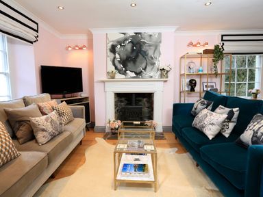 A living room with two sofas a glass coffee table and a fireplace at 16 Courtenay Street in Salcombe