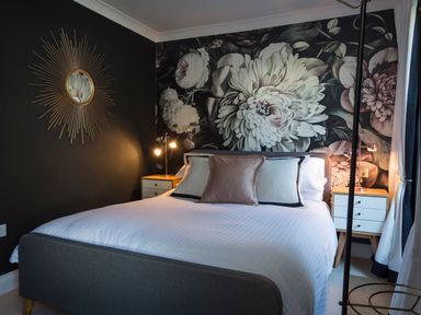A bedroom with a bed with white bedding and pillows floral wallpaper and bedside tables at 16 Courtenay Street in Salcombe