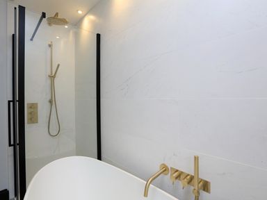 A bathroom with a shower area and a bathtub with gold fixtures at 16 Courtenay Street in Salcombe
