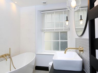 A bathroom with a freestanding bathtub and wall-mounted faucets a window with blinds and a sink with a wall-mounted faucet at 16 Courtenay Street in Salcombe