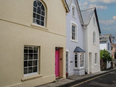 A street with houses featuring a pink door and windows at 16 Courtenay Street in Salcombe