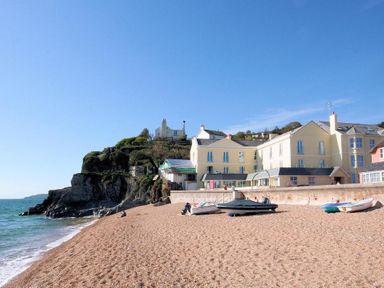 A pebble beach with boats and buildings near cliffs by the sea at 1 At The Beach in Torcross