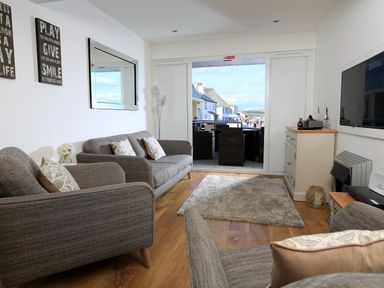 A living room with sofas a rug a wall mirror and a cabinet with a TV at 1 At The Beach in Torcross