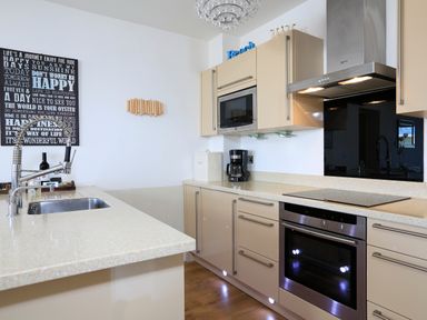 A kitchen with beige cabinets stainless steel oven and microwave coffee maker and sink with a modern faucet at 1 At The Beach in Torcross