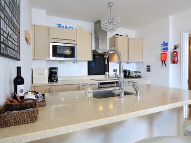 A kitchen with beige cabinets a sink with a flexible faucet a microwave coffee maker and toaster at 1 At The Beach Torcross