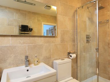 A bathroom with a sink soap dispenser toilet and glass shower enclosure at 1 At The Beach in Torcross