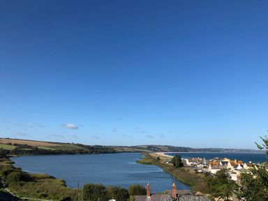 A coastal landscape with a river, greenery, houses, and a beach at 1 At The Beach in Torcross