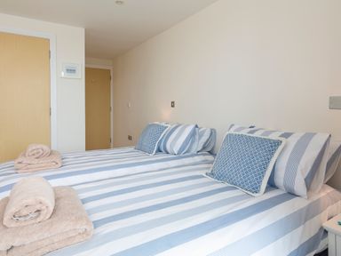 A bedroom with two beds with striped bedding and folded towels on top at 2 Ocean's Edge in Thurlestone