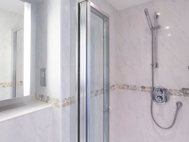 A bathroom shower area with tiled walls and a glass door at 2 Ocean's Edge in Thurlestone