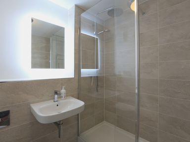 A bathroom with a wall-mounted sink and a glass-enclosed shower at 2 Poundstone Court in Salcombe