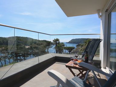 A balcony with two chairs a small table with wine and snacks overlooking a coastal landscape at 2 Poundstone Court in Salcombe
