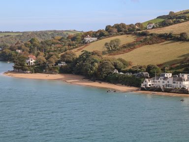 A coastal scene with houses on a hillside by a sandy beach and water at 2 Poundstone Court in Salcombe