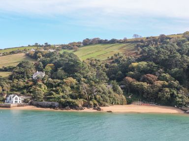 A coastal scene with houses near a beach and green hills at 2 Poundstone Court in Salcombe