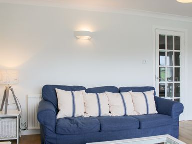 A living room with a blue sofa and cushions at 2 Poundstone Court in Salcombe