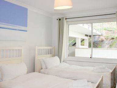 A bedroom with two beds and a window at 2 Poundstone Court in Salcombe