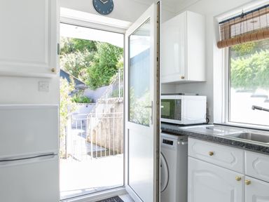 A kitchen door open to an outdoor area with stairs and greenery at 2 Rockmount in Salcombe
