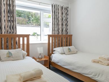 A bedroom with two single beds with wooden frames and white bedding at 2 Rockmount in Salcombe
