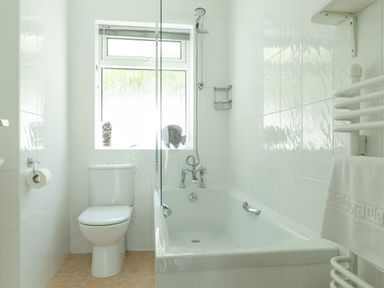 A bathroom with a bathtub shower toilet and towel rack at 2 Rockmount in Salcombe