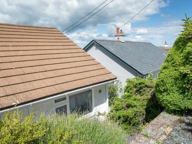 Two houses with sloped roofs surrounded by bushes and plants at 2 Rockmount in Salcombe