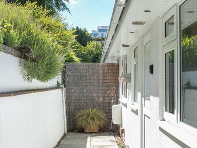 An outdoor passageway with white walls plants and windows at 2 Rockmount in Salcombe
