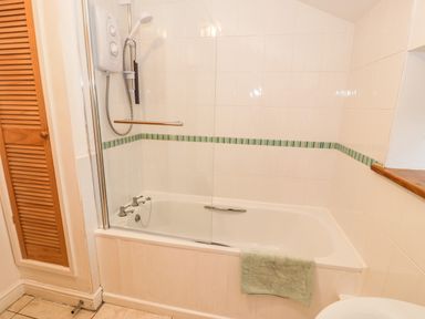 A bathroom with a bathtub shower and a green towel hanging on the tub at Y Bwthyn in Elidir Fach Mountain near Llanberis