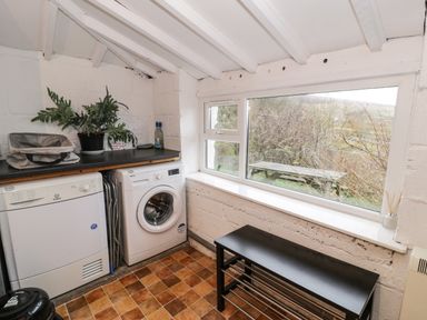 A utility room with a washing machine dryer countertop and bench at Y Bwthyn Elidir Fach Mountain near Llanberis