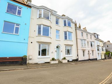 A street view of multi story buildings including a cream building with an arched entrance and a blue building at 3 Dartview Dartmouth