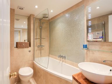 A bathroom with a bathtub and shower, a toilet, and a sink with a mirror above at 3 Dartview in Dartmouth