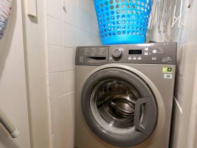 A laundry room with a front loading washing machine and a blue laundry basket on top at 3 Dartview in Dartmouth