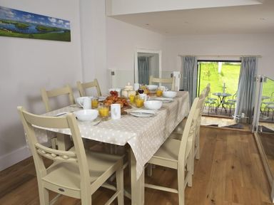 A dining area with a table set for breakfast including croissants orange juice and bowls at 3 Eddystone Row in Salcombe