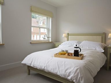 A bedroom with a bed with breakfast on it and two windows at 3 Eddystone Row in Salcombe