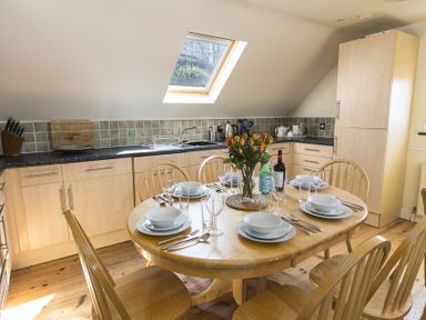 A kitchen with a wooden dining table set for six and a skylight window at 4 Armada House in Hope Cove