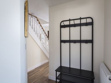 A hallway with a staircase and a black coat rack bench at 4 Armada House in Hope Cove