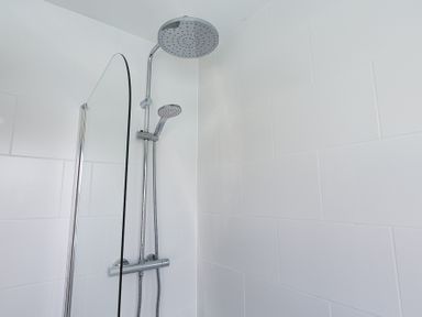 A shower with a large round showerhead and a handheld showerhead in a tiled bathroom at 4 Armada House in Hope Cove