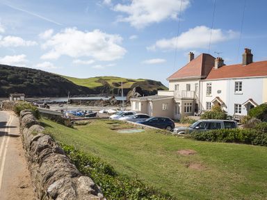 A coastal area with houses cars grass and boats near the water at 4 Armada House in Hope Cove