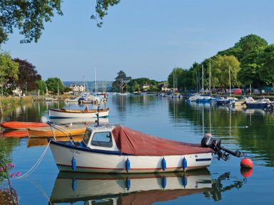 A river with boats moored along the banks and trees on both sides at Cowslip Cottage in Frogmore