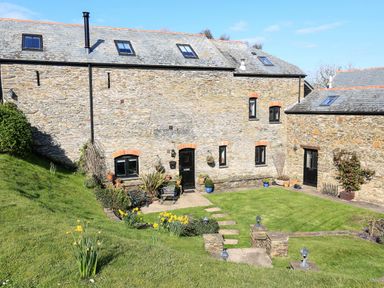 A stone house with a garden and daffodils in the lawn at Cowslip Cottage in Frogmore