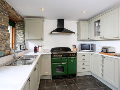 A kitchen with stone wall window and green oven at Cowslip Cottage in Frogmore
