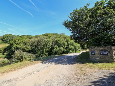 A gravel road with trees and stone signs reading Winslade Court and Winslade Manor in Frogmore