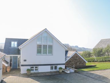A white house with a blue door and large windows with shutters at Sea Peep in Thurlestone