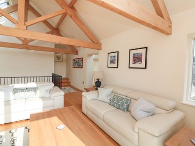 A living room with wooden beams two white sofas a wooden coffee table and framed pictures on the wall at Sea Peep in Thurlestone