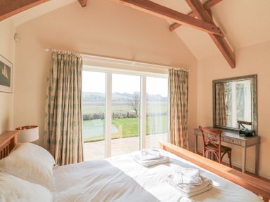 A bedroom with a bed folded towels curtains and a dressing table with a chair at Sea Peep in Thurlestone