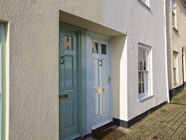Two front doors numbered six and seven on a white building with a paved pathway at 7 Charles Street in Dartmouth
