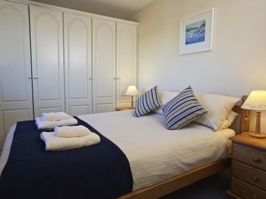 A bedroom with a double bed two bedside tables and lamps and built-in wardrobes at Amberley in Dartmouth